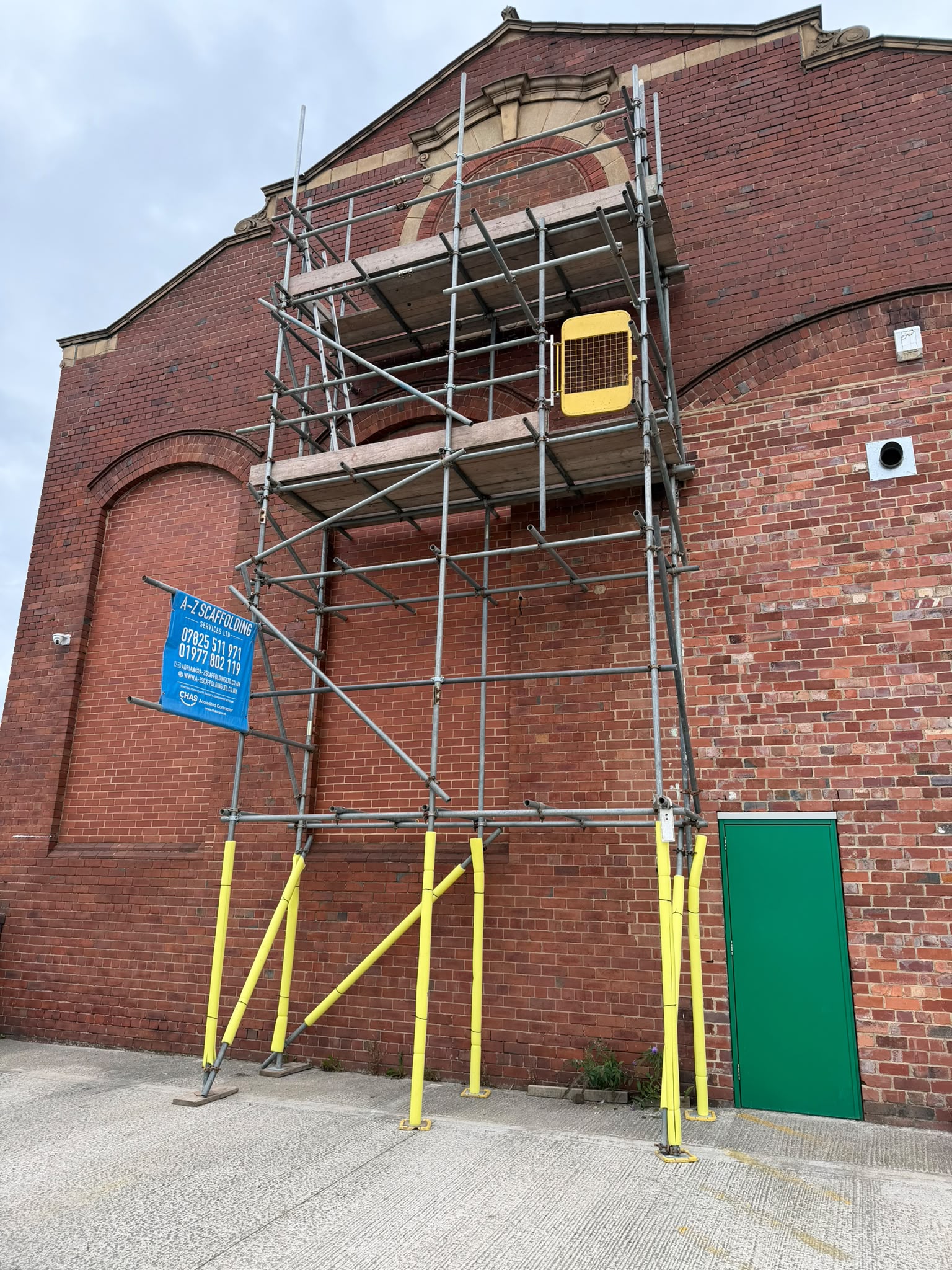 Scaffolding tower against a brick industrial building for commercial access work